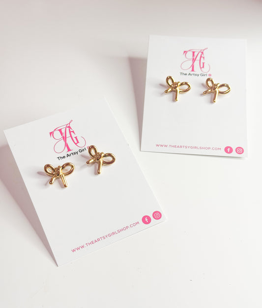 Close-up image of gold tarnish-free bow stud earrings with a sleek, shiny finish. These delicate earrings feature a classic bow design, perfect for adding a touch of elegance and charm to any outfit.