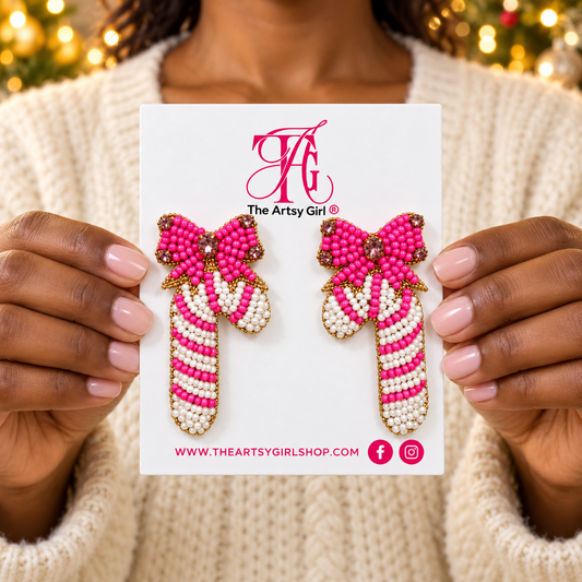 Woman holding The Artsy Girl card with pink and white beaded candy cane earrings topped with pink bows.