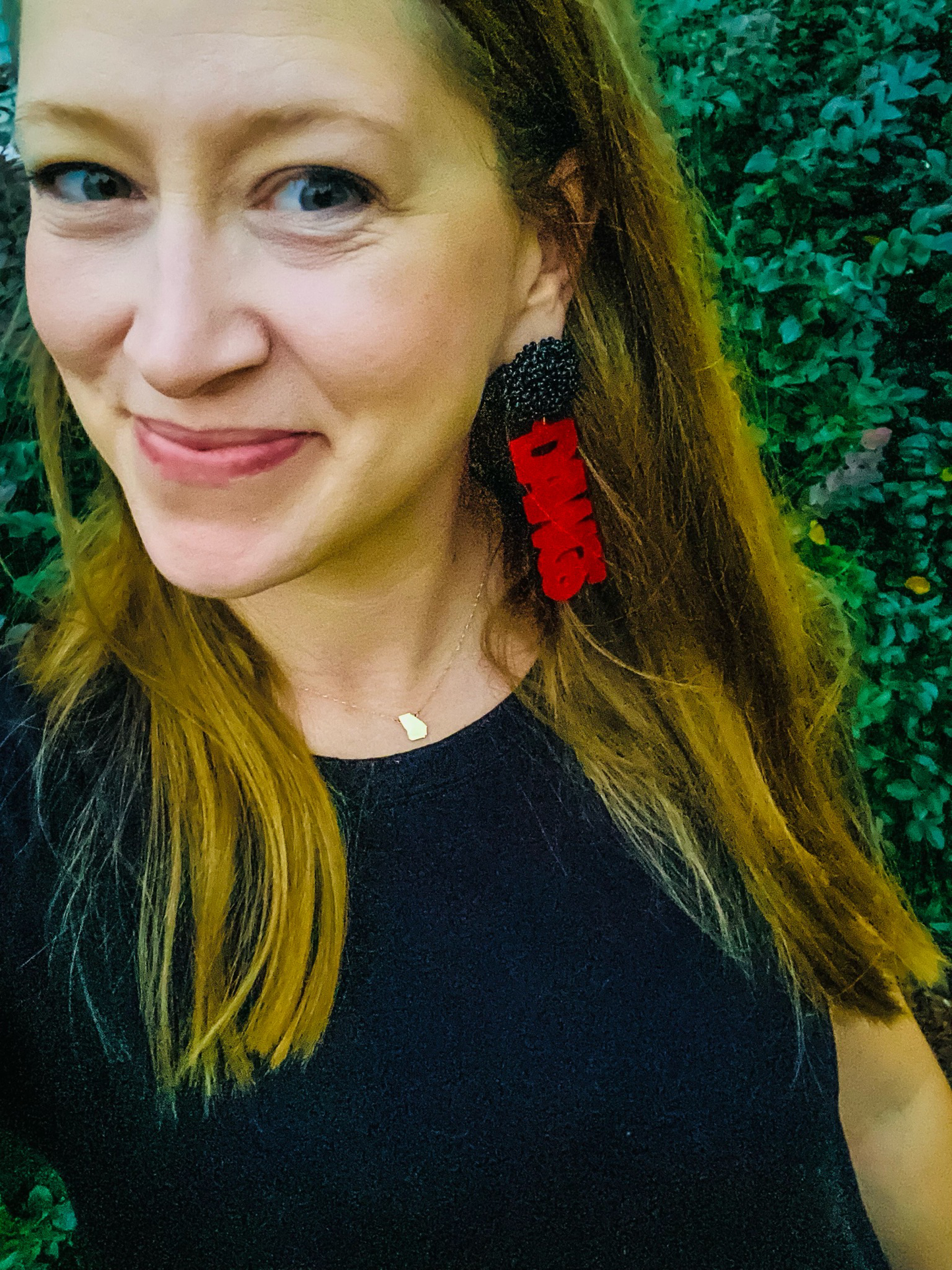 Girl wearing handmade Georgia Bulldog earrings with a black seed bead topper and the word ‘Dawgs’ spelled out.