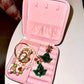 Pink jewelry case with green and pink jewelry on a white surface