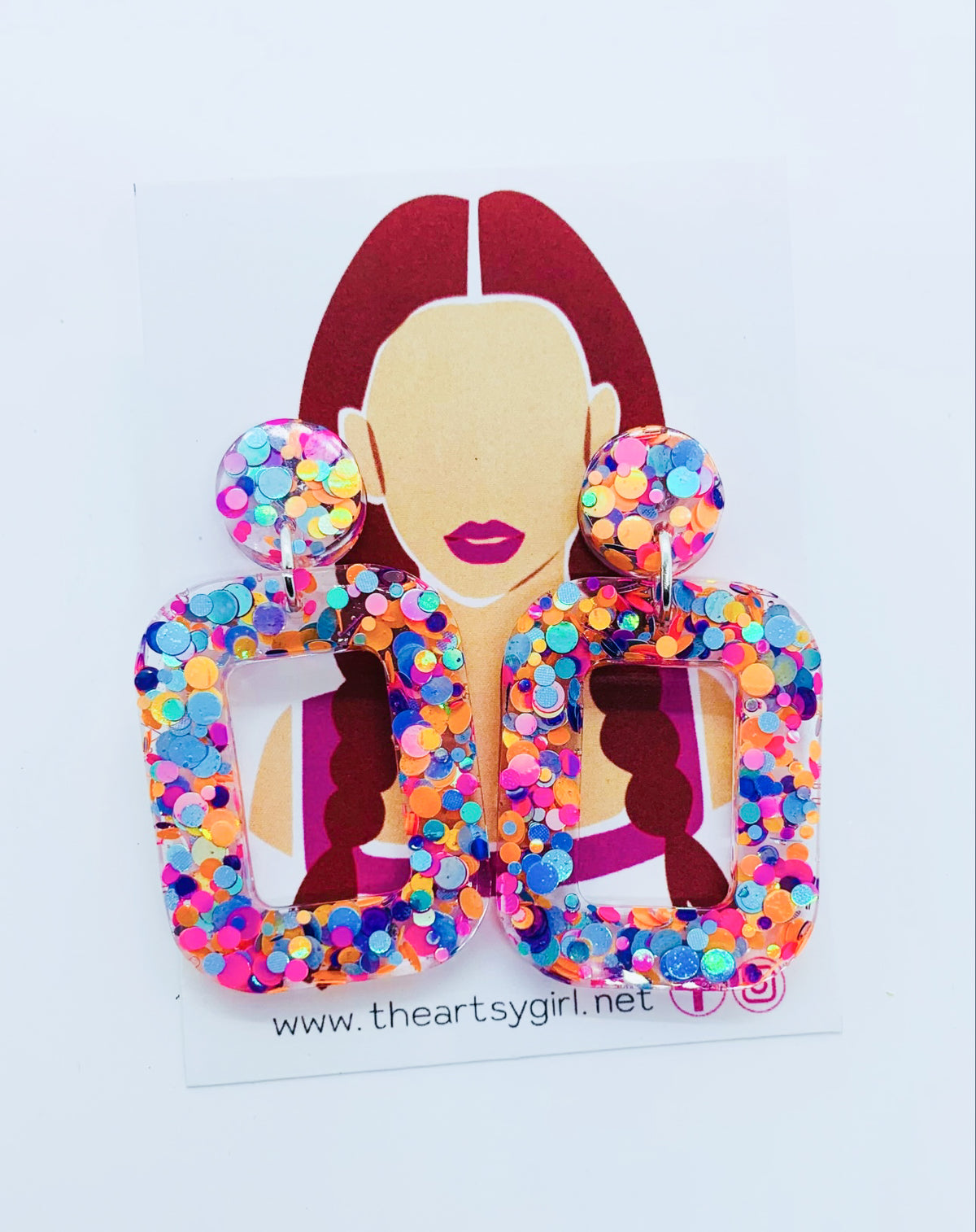 A pair of multicolored round square earrings with a glittery finish, featuring a design that resembles a woman's profile with earrings and a name tag.