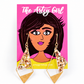 A pair of gold-toned geometric drop earrings with glittery gold and gold triangular charms, displayed on a pink backing card illustrated with a woman's portrait and the text 'The Artsy Girl'.