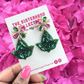Hand holding Ivy Inspired Earrings with a pink background 