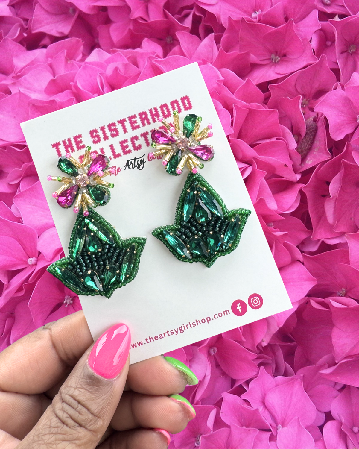 Hand holding Ivy Inspired Earrings with a pink background 