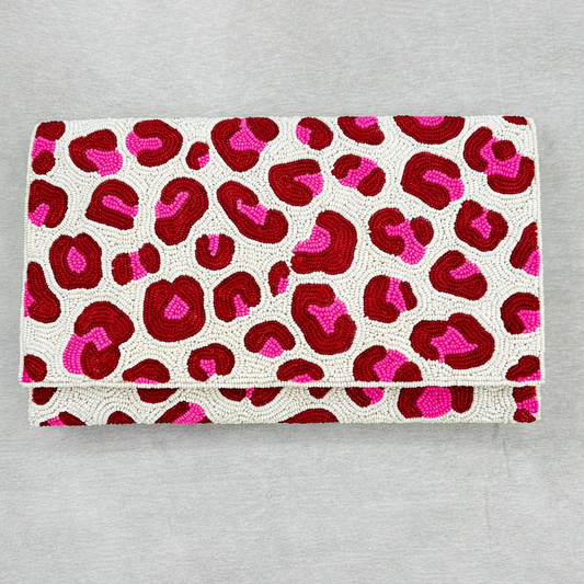 Pink and red spotted hand-beaded clutch purse on a neutral background showing detailed beadwork and fold-over design.