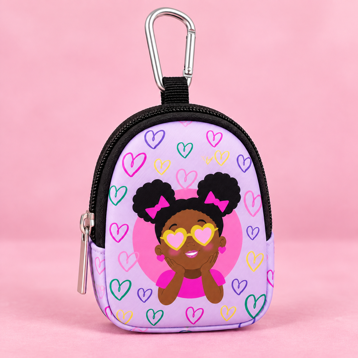 A small zippered coin purse with a carabiner clip, featuring a cartoon girl with heart-shaped sunglasses and colorful hearts on a light purple background, set against a solid pink backdrop.