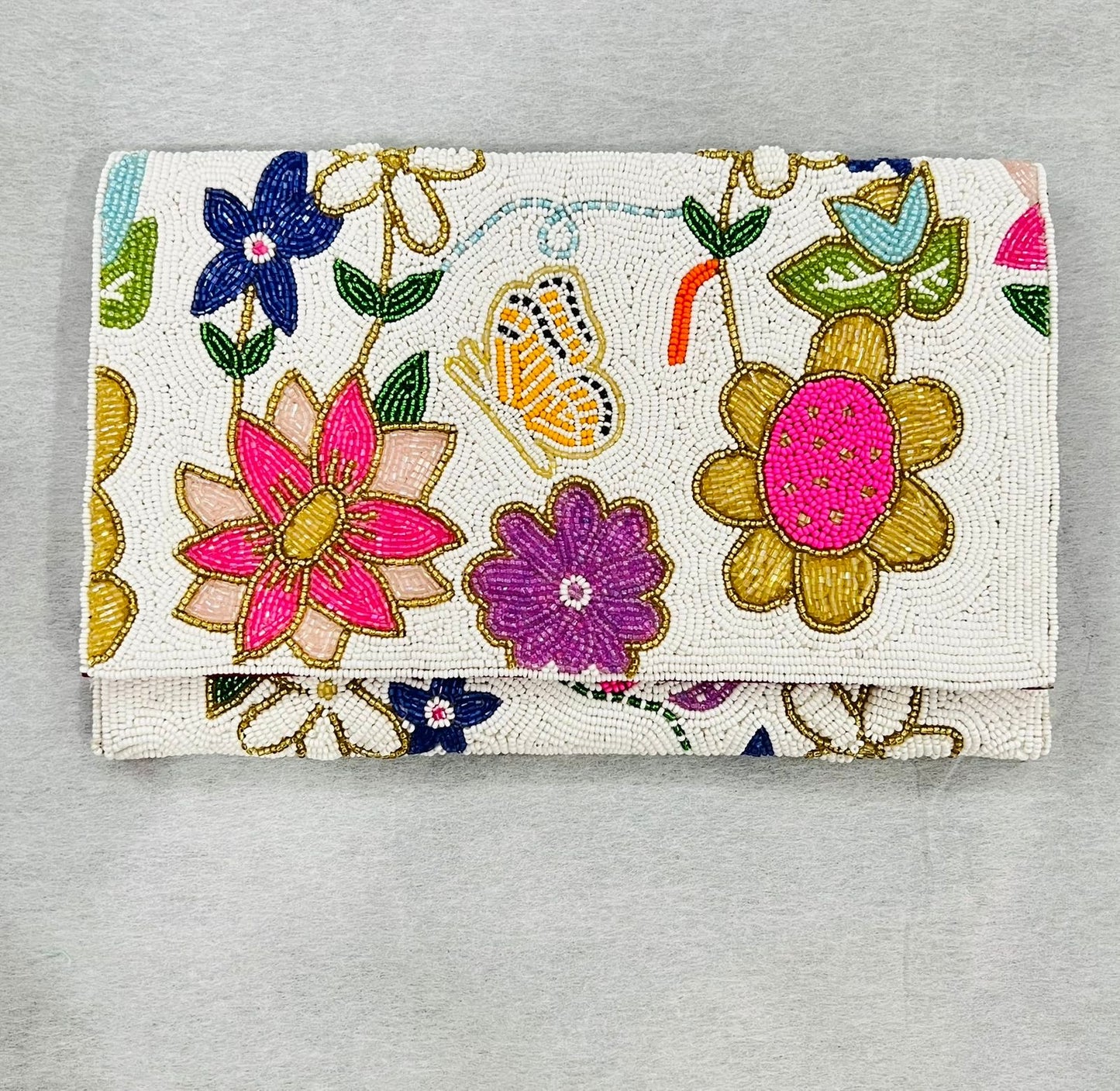 Embroidered clutch with floral and butterfly design on a gray background
