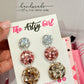 A pair of metallic earrings with rose gold, silver, and gold colors, displayed on a card with 'The Artsy Girl' branding.
