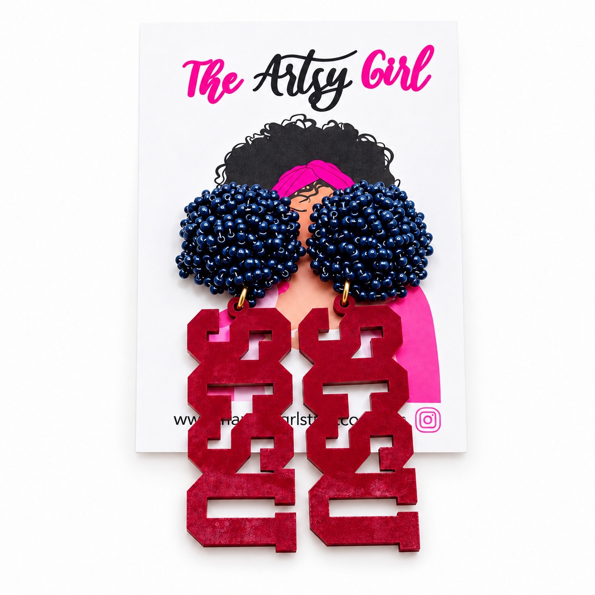 A pair of statement earrings displayed on a white backing card. The earrings feature two large, dark blue beaded pom-pom tops with gold-tone hooks, and long, chunky garnet letters spelling 'SCSU' below.
