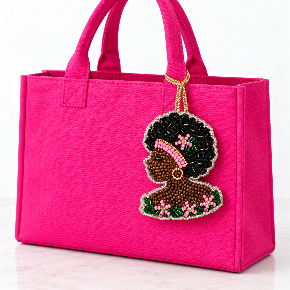 Beaded Black woman profile charm with a pink headband and floral details hanging from a solid hot pink tote.