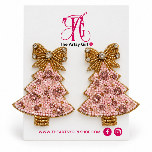 Blush pink beaded Christmas tree earrings with pink gemstones and gold bows on The Artsy Girl card against a white background.