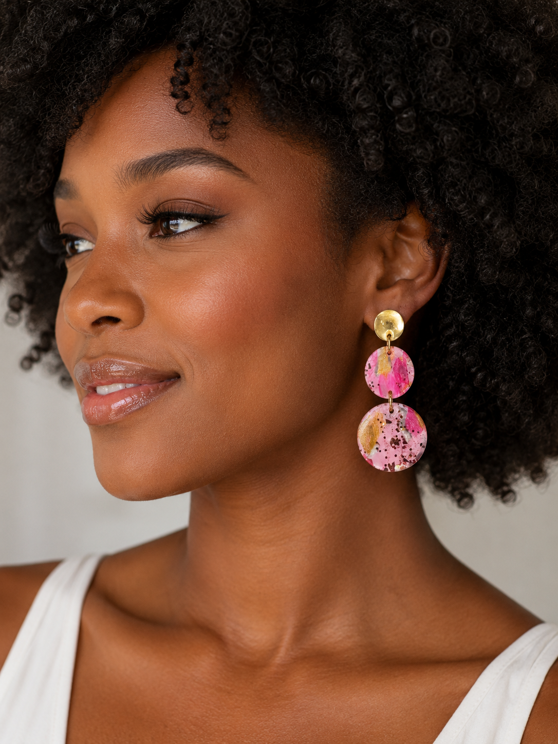 Woman wearing colorful earrings with a neutral background