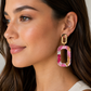 Woman wearing a colorful earring with a neutral background