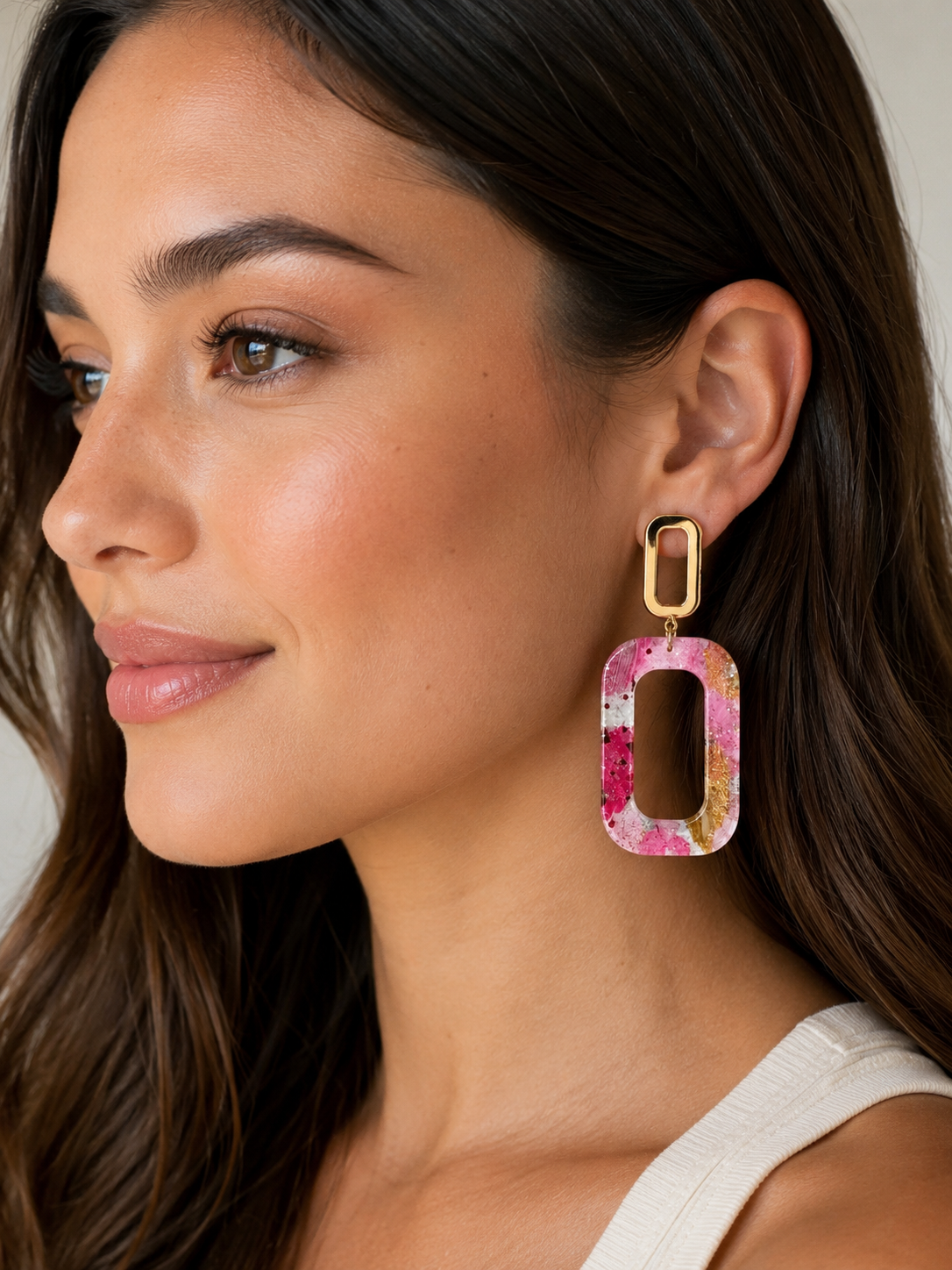 Woman wearing a colorful earring with a neutral background