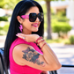 Woman in a pink sleeveless top and oversized sunglasses wearing pink glitter lightning bolt earrings outdoors.