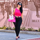 Woman styling pink lightning bolt earrings with a pink top, black pants, and pink handbag in front of a mural.