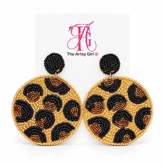 Round gold beaded leopard earrings with black and bronze spots and black beaded stud tops on The Artsy Girl card.