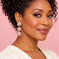 Woman wearing light pink three-tier crystal flower earrings with a cream blouse against a blush background.