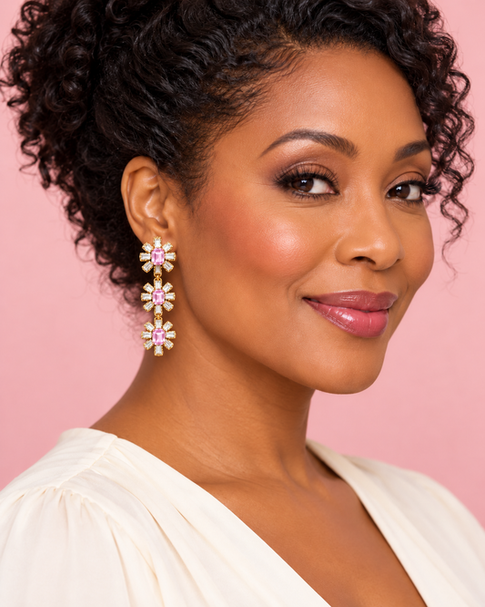 Woman wearing light pink three-tier crystal flower earrings with a cream blouse against a blush background.