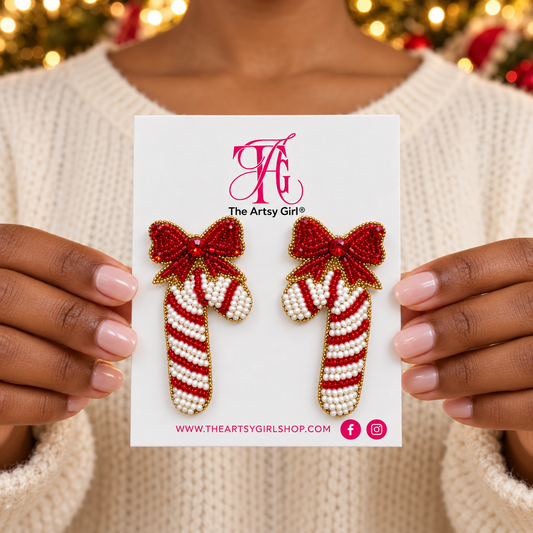 Woman holding The Artsy Girl card with red and white beaded candy cane earrings topped with red bows.